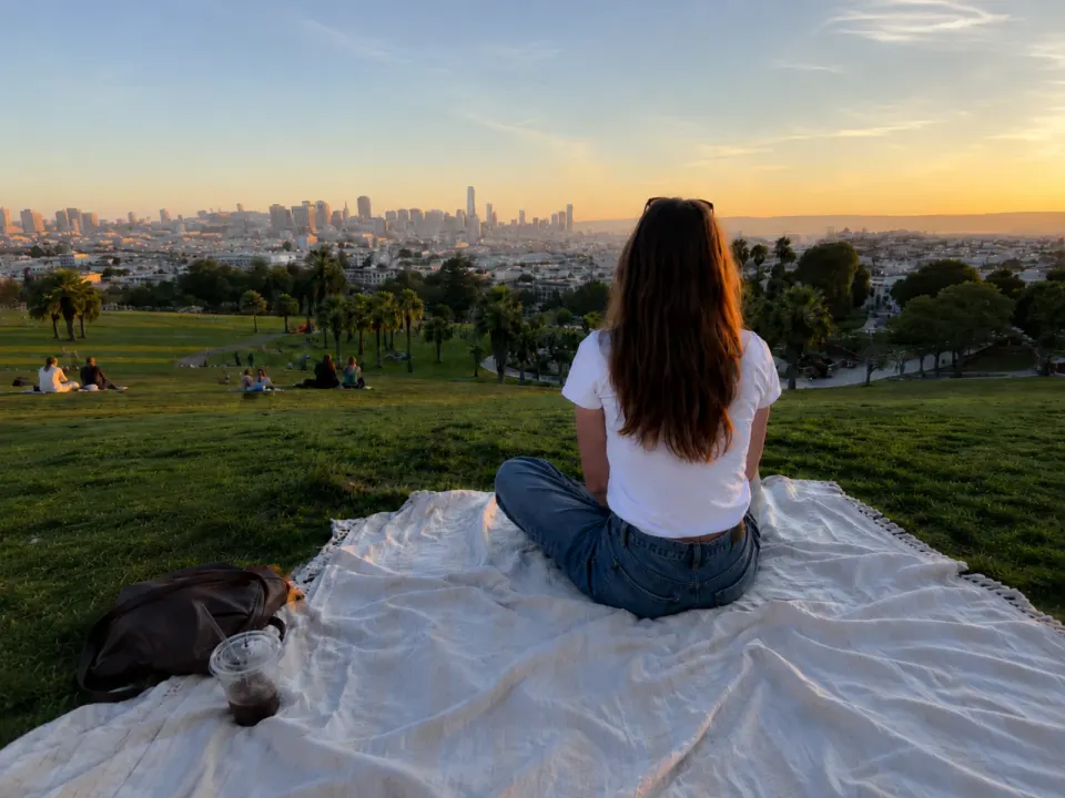 A woman near the center, with a large picnic blanket filling the foreground